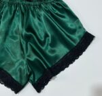 نمای نزدیک بافت پارچه ساتن سبز و دوخت ظریف گیپور لبه شورتک لباس خواب