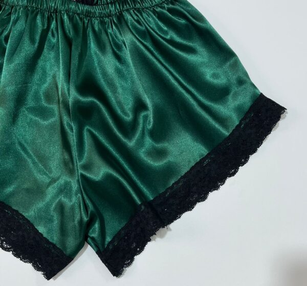 نمای نزدیک بافت پارچه ساتن سبز و دوخت ظریف گیپور لبه شورتک لباس خواب