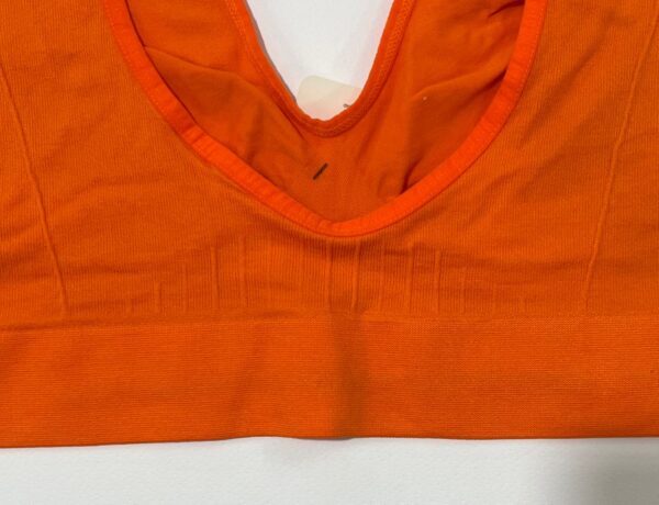 نمای نزدیک لوگوی نایک و بافت کبریتی نیم‌تنه ورزشی زنانه