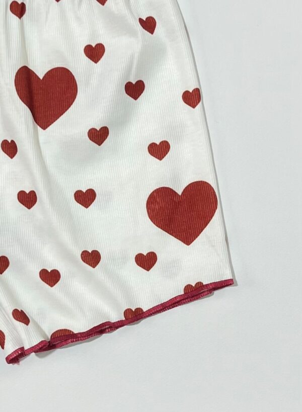 جزئیات شلوارک کبریتی سفید با طرح قلب قرمز و دوخت دالبر در لبه پایین