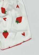 نمای نزدیک از پارچه کبریتی سفید با چاپ توت فرنگی و لبه دوزی قرمز رنگ