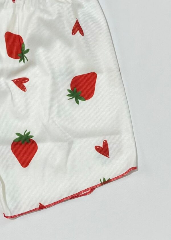 نمای نزدیک از پارچه کبریتی سفید با چاپ توت فرنگی و لبه دوزی قرمز رنگ