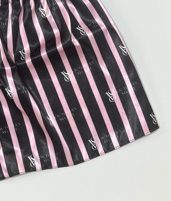 نمای نزدیک پارچه ساتن راه‌راه مشکی و صورتی با لوگوی طرح ویکتوریا سیکرت روی لباس خواب