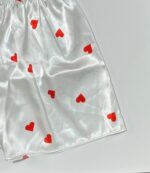 نمای نزدیک دوخت و پارچه ساتن سفید با چاپ قلب‌های کوچک قرمز