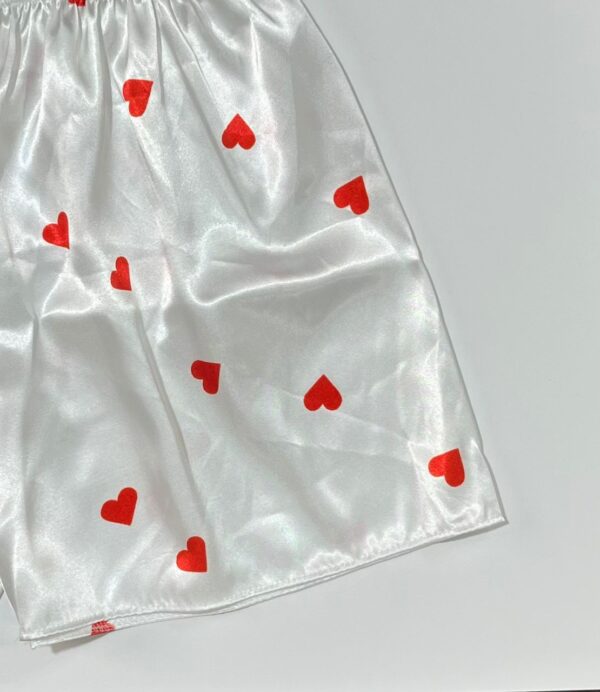نمای نزدیک دوخت و پارچه ساتن سفید با چاپ قلب‌های کوچک قرمز